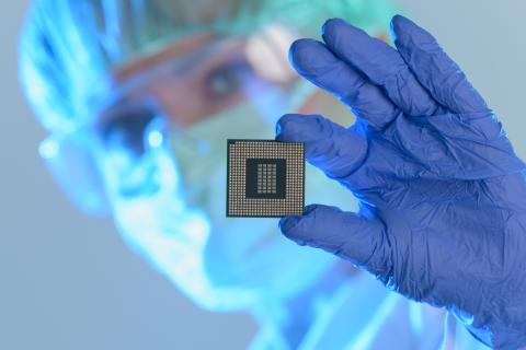 Woman in scrubs, mask and gloves holding microchip